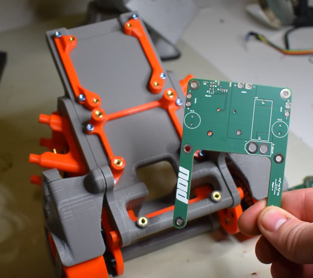 A hand fitting a circuit board into the 3D-printed Bobble-Bot chassis on a workbench